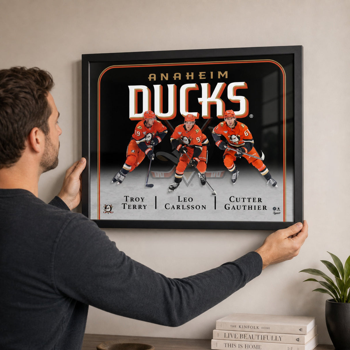 Man hanging the Anaheim Ducks Triple Player Collage Frame on living room wall – install scene – Frameworth