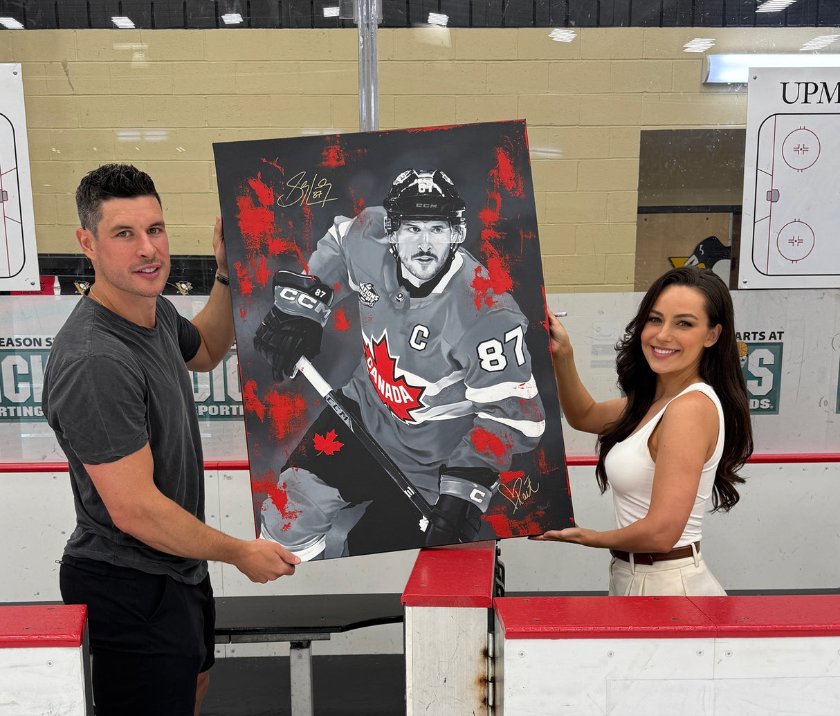 Sidney Crosby and artist Kait Schoeb proudly holding the dual-signed Four Nations Gold original painting
