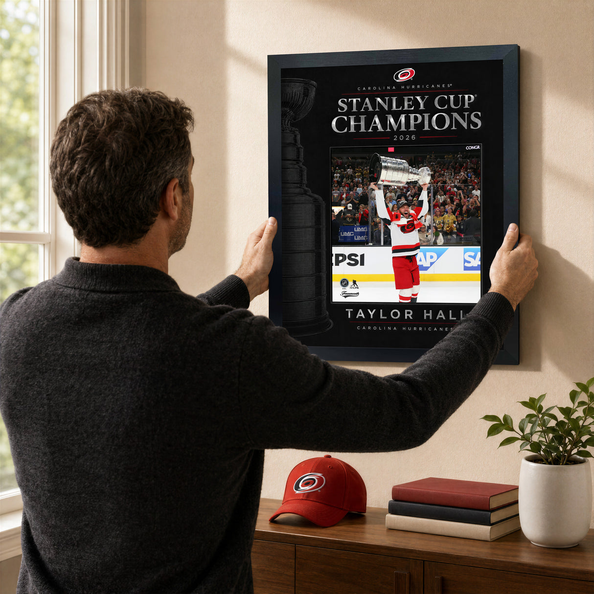 Taylor Hall 16x20 PhotoGlass frame Carolina Hurricanes 2026 Stanley Cup Champions shown being hung as framed wall art